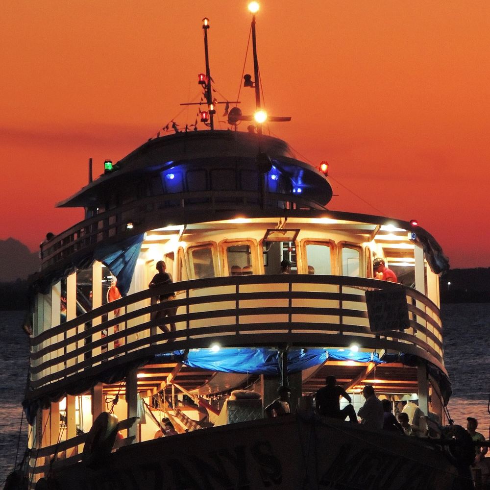 Embarcación iluminada navegando al atardecer